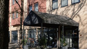 A hotel entrance with a covered waiting area, bicycles parked outside, and a red carpet leading to the entrance. - Flemings Hotel München-schwabing (Munich)