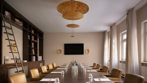 A conference room with a long table, chairs, a TV, and a bookshelf. - Flemings Hotel München-schwabing (Munich)