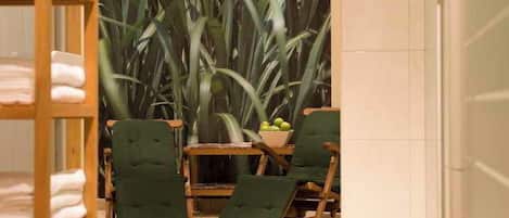 Una habitación con una silla de madera, una mesita y una planta.