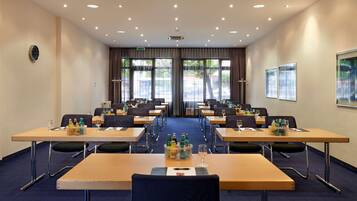 A conference room with tables, chairs, and a clock on the wall.