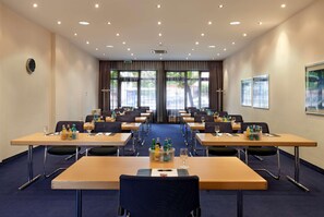 Ein Konferenzraum mit Tischen, Stühlen und einer Uhr an der Wand.