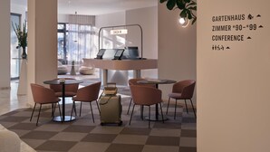 Un moderno vestíbulo de hotel con mostradores de recepción, áreas de descanso y una gran planta.