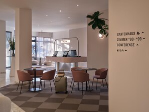 Een moderne hotel lobby met incheckbalies, zithoeken en een grote plant.