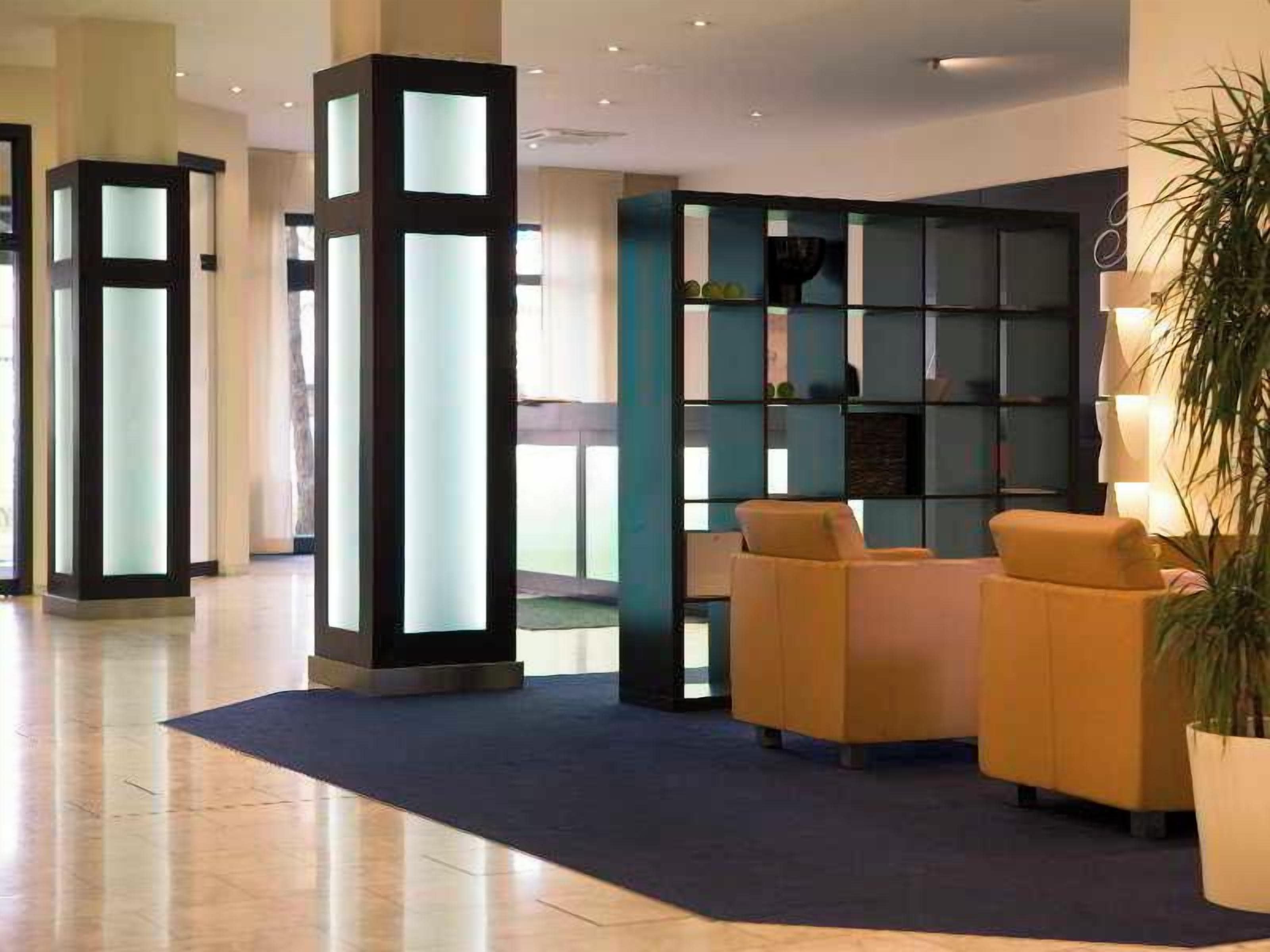 A lobby with a reception desk, seating area, and a large bookshelf.