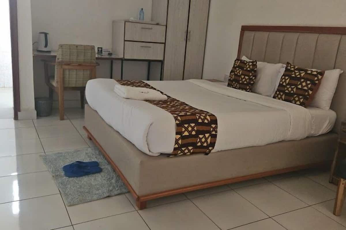 A neatly arranged bedroom with a bed, a desk, and a chair.