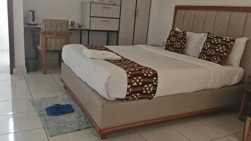 A neatly arranged bedroom with a bed, a desk, and a chair.