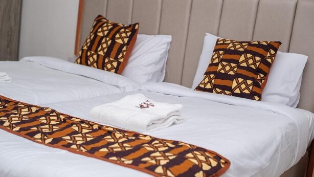 A hotel room with two beds, each with white linens and patterned throw blankets. - Vijiji Hotel and Conference Eldoret (Eldoret)