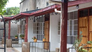 A building with a covered porch, wooden doors, and potted plants. - Vijiji Hotel and Conference Eldoret (Eldoret)