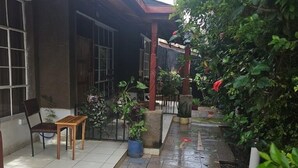 A covered outdoor area with a tiled floor, a wooden bench, and various potted plants. - Vijiji Hotel and Conference Eldoret (Eldoret)