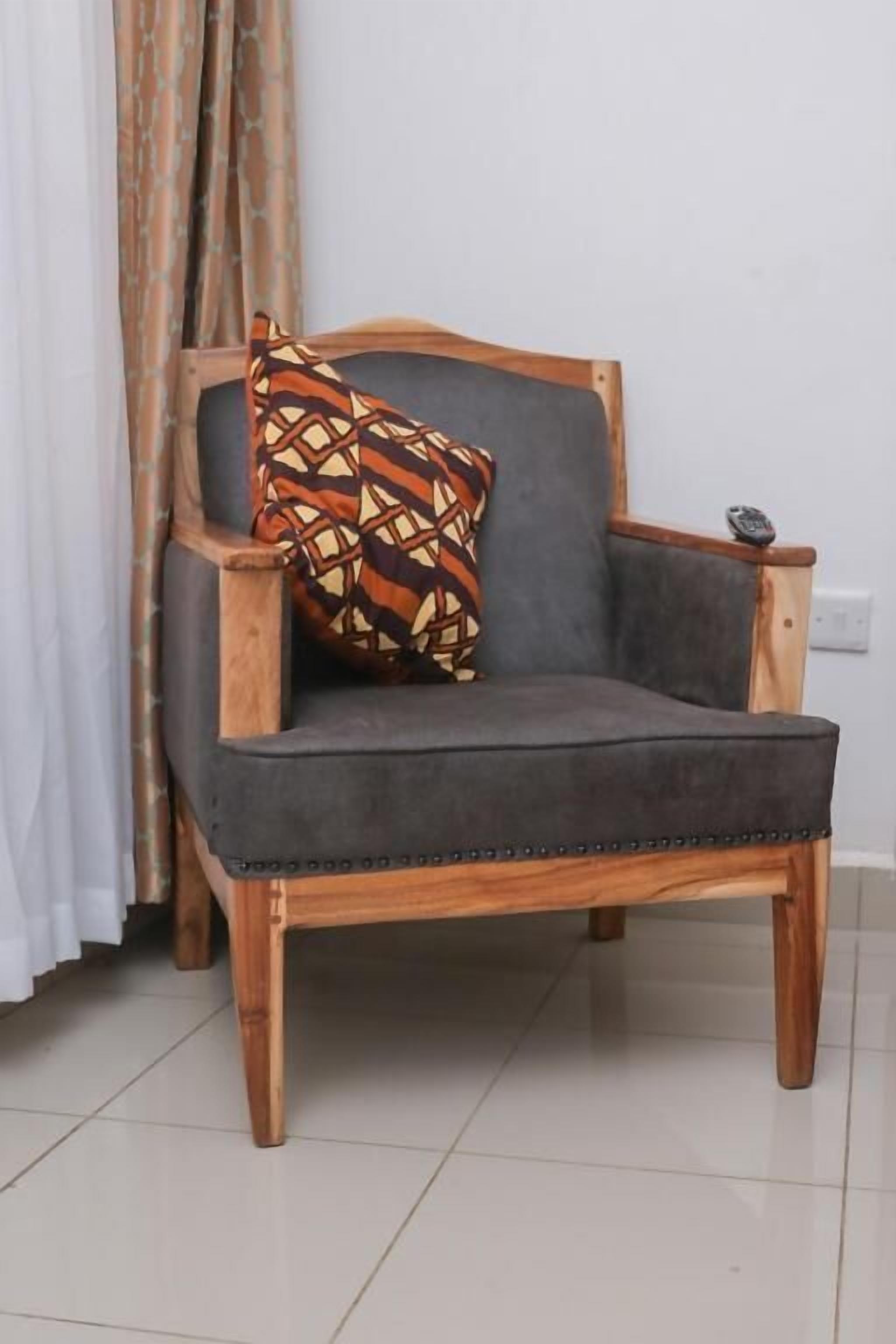 A wooden armchair with a grey cushion and a patterned pillow.