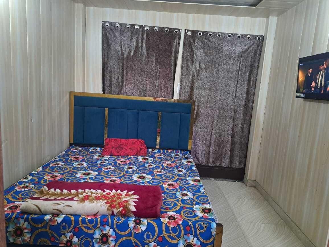 Quarto com cama, cortinas e televisão na parede.