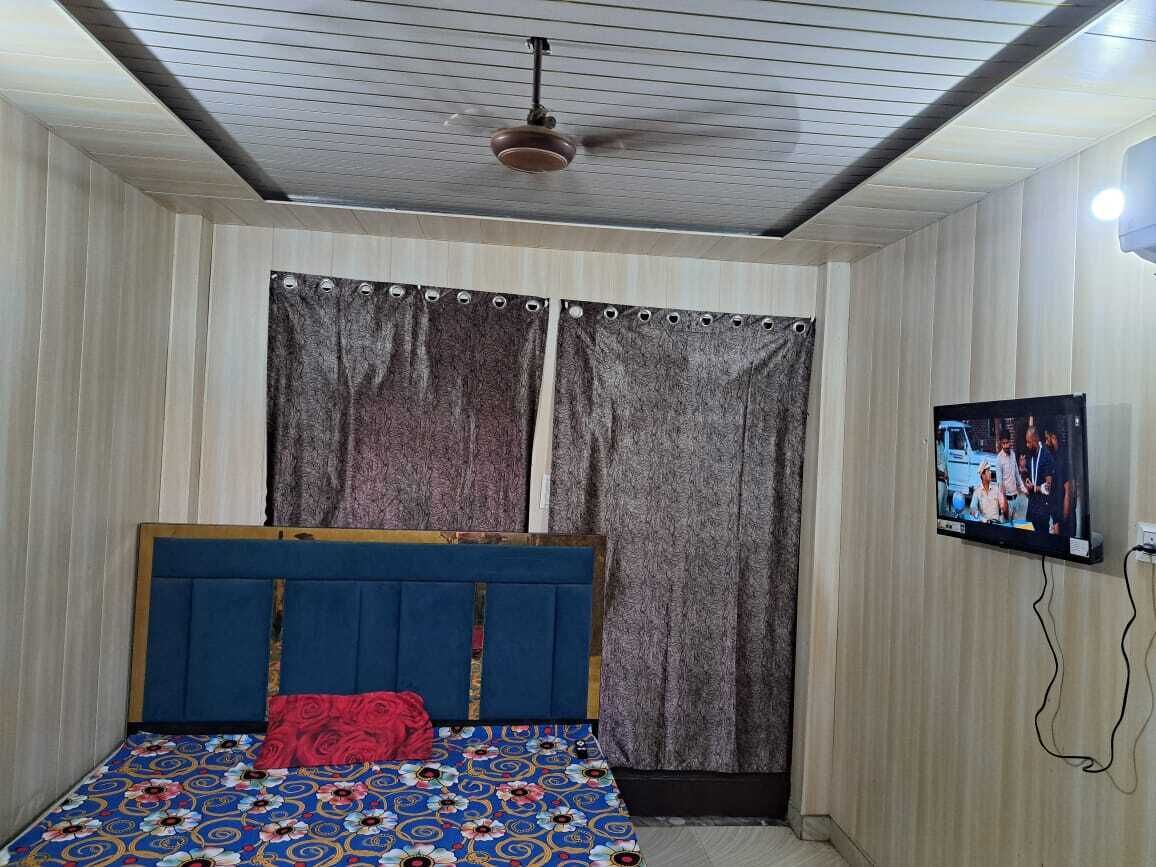 A bedroom with a bed, curtains, a ceiling fan, and a TV.