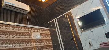 Habitación de hotel con pared de diseño, detalles en mármol, televisor de pantalla plana y aire acondicionado.