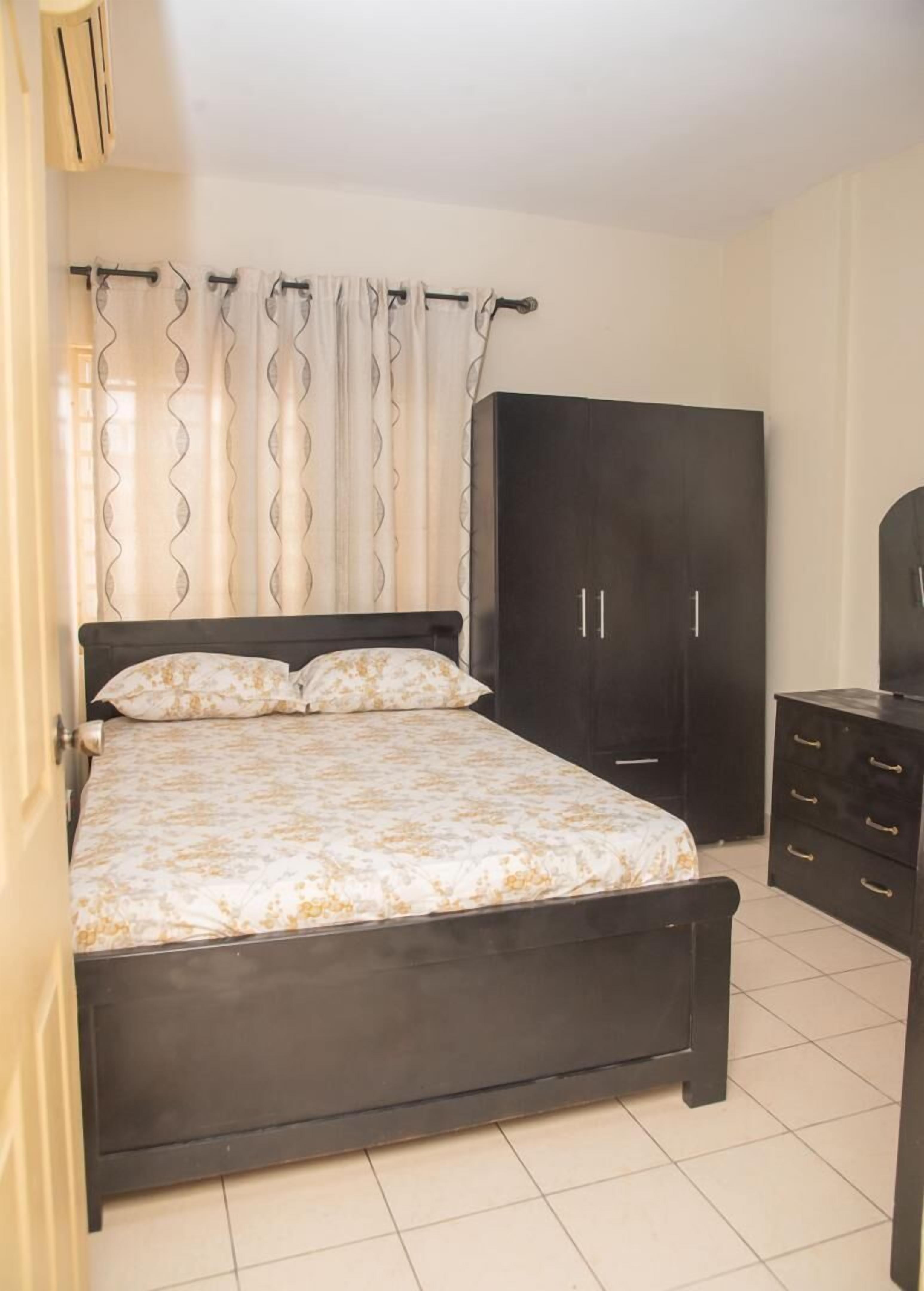 A bedroom with a bed, a wardrobe, and a dresser.