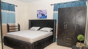 A bedroom with a large bed, a wardrobe, and a small table with a plant. - Regimanuel Estates  (Kwabenya)