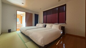 A bedroom with a large bed, a sliding door leading to another room, and a window with blinds. - BAY LUNA  (Hakodate)