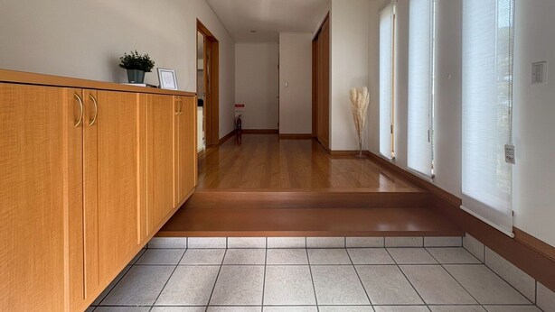 A hallway with wooden cabinets, a tiled floor, and large windows with blinds. - BAY LUNA  (Hakodate)