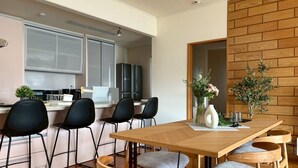 A modern kitchen with white cabinets, a black refrigerator, and a dining area with a wooden table and four chairs. - BAY LUNA (Hakodate)