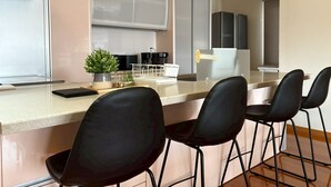 A modern kitchen with a central island, black bar stools, and a potted plant. - BAY LUNA (Hakodate)
