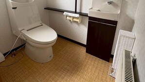 A small, compact bathroom with a toilet, a sink, and a radiator. - BAY LUNA  (Hakodate)
