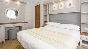 Un dormitorio con cama, espejo redondo, tocador y estantería empotrada.