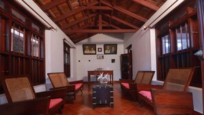 A room with wooden furniture, a tiled floor, and a high ceiling with exposed beams. - Vilayara Heritage Retreat (Kozhikode)