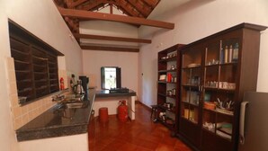 A kitchen with a tiled floor, a built-in oven, a sink, and a cabinet with glass doors. - Vilayara Heritage Retreat (Kozhikode)