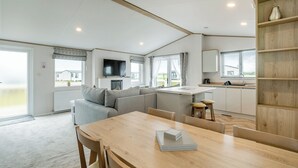 A modern RV interior with a dining area, kitchen, and living space.