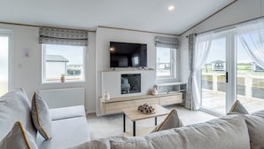 A modern living room with a flat-screen TV, a fireplace, and a balcony with a view.