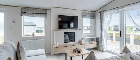 A modern living room with a flat-screen TV, a fireplace, and a balcony with a view.