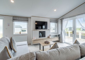 Een moderne woonkamer met een flatscreen-televisie, een open haard en een balkon met uitzicht.