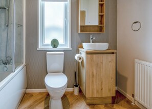 A bathroom with a toilet, a sink, a mirror, and a window.