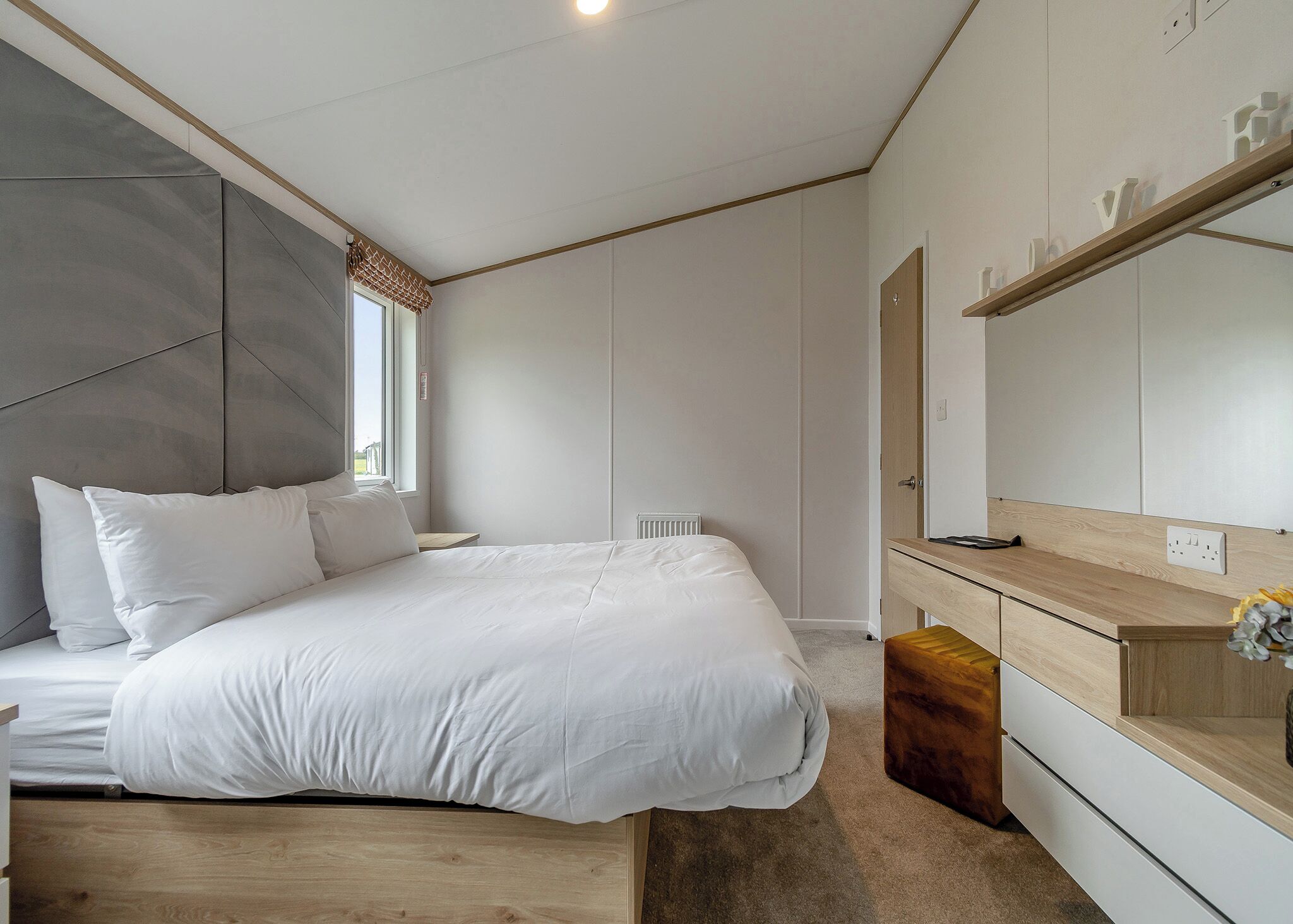 A bedroom with a bed, a bedside table, a dresser, a mirror, and a radiator.