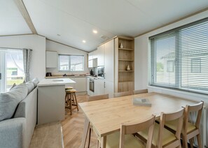 A modern kitchen with a central island, wooden chairs, and a dining table.