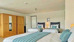 Een hotelkamer met twee bedden, een garderobe, een spiegel en een plafondlamp.