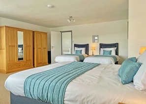 A hotel room with two beds, a wardrobe, a mirror, and a ceiling light.