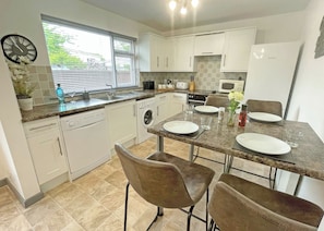 A modern kitchen with white cabinets, a built-in oven, a microwave, and a dining area with a table set for two.