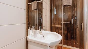 A bathroom with a white sink, two mirrors, and a glass-enclosed shower.