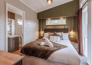 Een hotelkamer met een bed, nachtkastje, lamp en een raam met gordijnen.