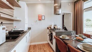 A modern kitchen with a central island, a dining area with red chairs, and a large window with curtains.