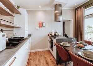 Une cuisine moderne avec un îlot central, un coin repas avec des chaises rouges et une grande fenêtre agrémentée de rideaux.