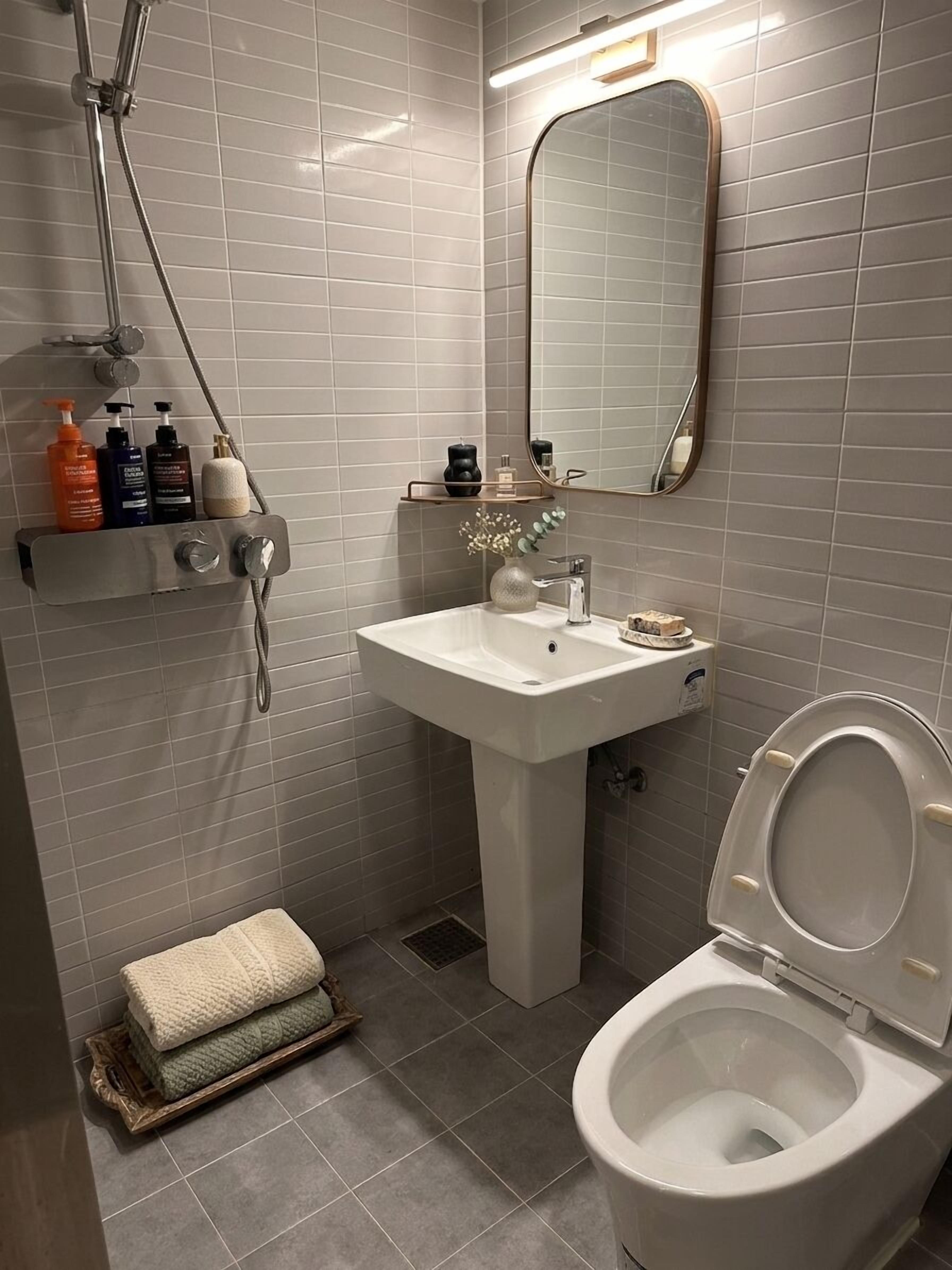 Ein Badezimmer mit weißem Waschbecken, Toilette, Dusche und Spiegel.