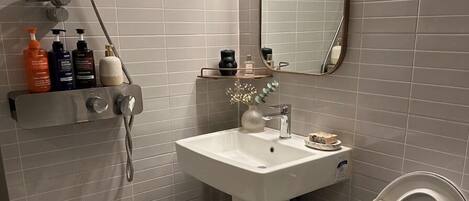 Un baño con un lavabo blanco, un inodoro, una ducha y un espejo.