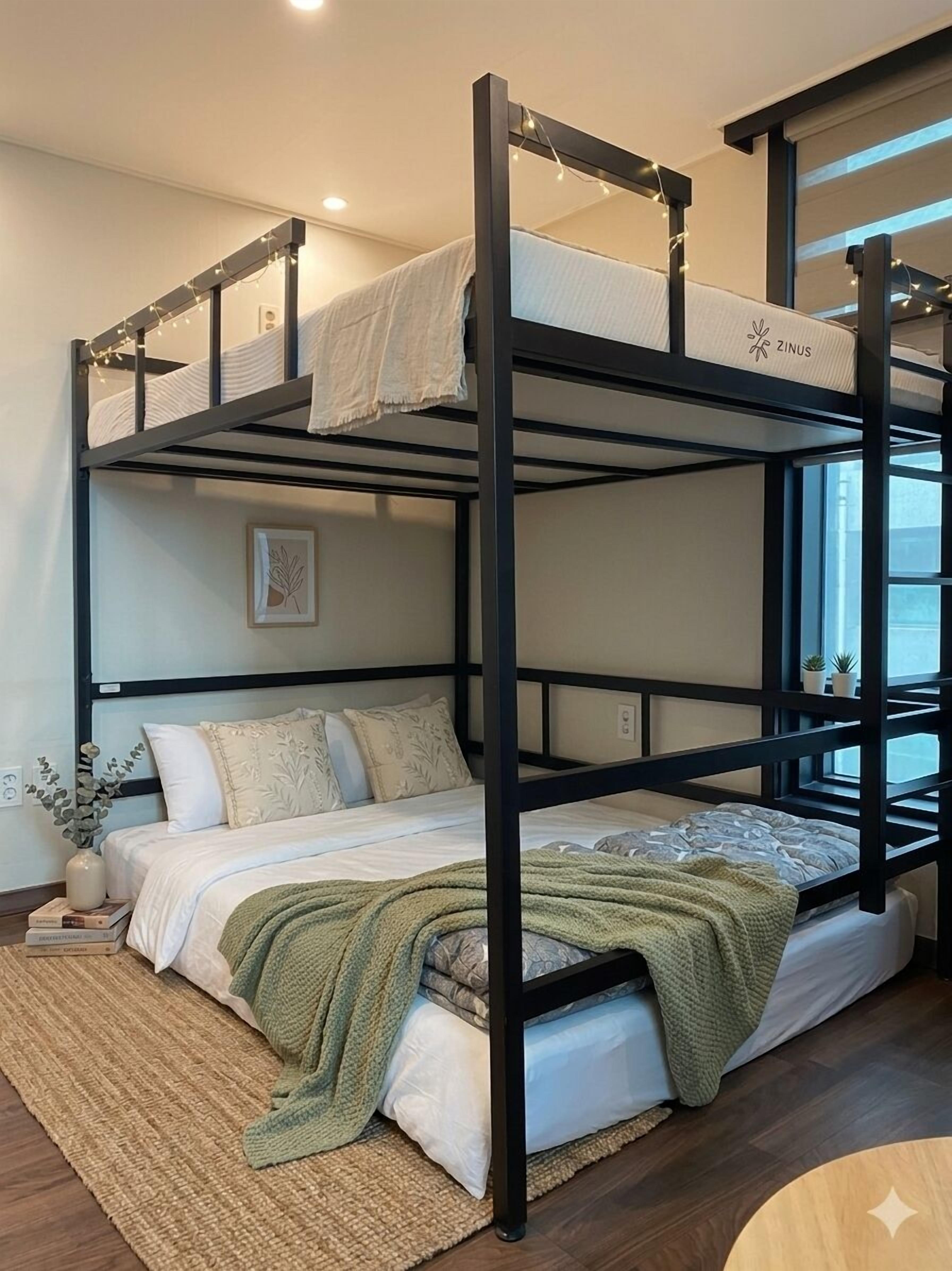 A bunk bed with a green blanket, a small plant, and a framed picture on the wall.