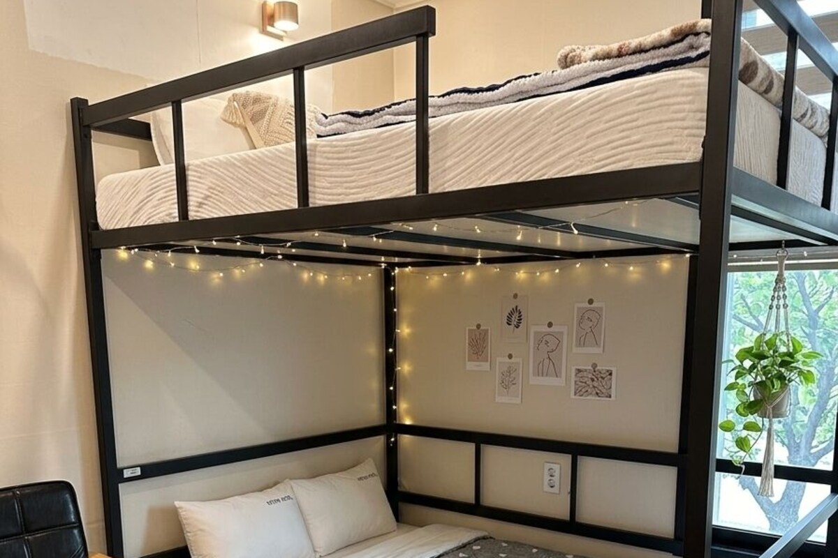 A bunk bed room with a desk, a chair, and a potted plant.