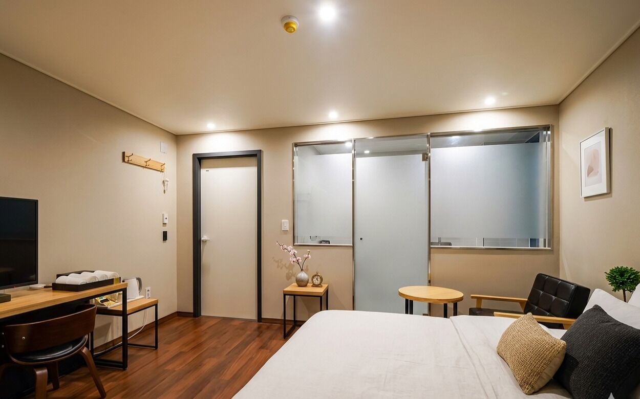 Une chambre d’hôtel équipée d’un lit, d’un bureau, d’une chaise, d’une petite table, d’un téléviseur et d’une armoire.