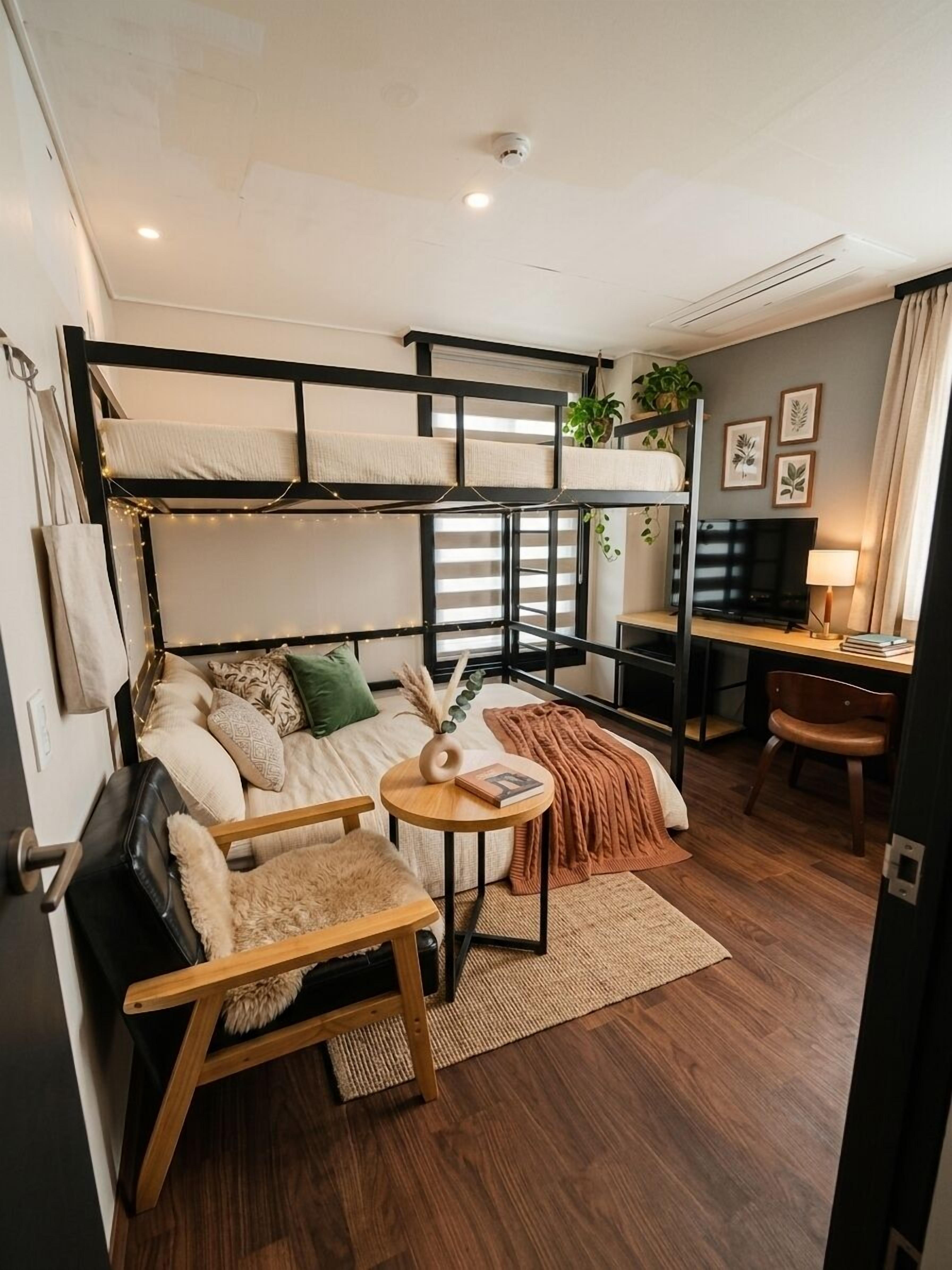 Un espacio habitable compacto con literas, un sofá, una mesita, un televisor y un escritorio.