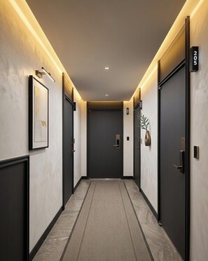 A modern hallway with a marble floor, framed artwork, and a door with a number sign. - Billy Hotel (Busan)