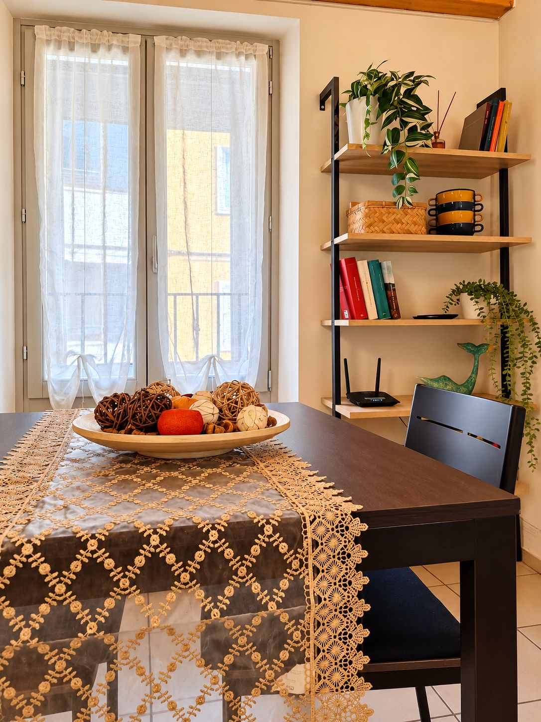Une table à manger agrémentée d’un chemin de table décoratif, une assiette de fruits et une chaise.