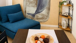 A living room with a sofa, a table with a plate of snacks, a wall-mounted TV, and a shelf with a plant. - Casa Giorgia, a confortable and amazing place in centre of Cormons (Cormons)